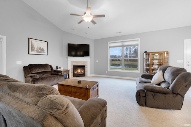 carpeted living room with ceiling fan, a tile fireplace, and vaulted ceiling