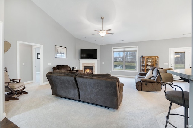 living room with a tile fireplace, ceiling fan, light colored carpet, and vaulted ceiling