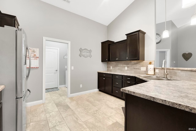 kitchen featuring high vaulted ceiling, hanging light fixtures, sink, dark brown cabinetry, and stainless steel refrigerator