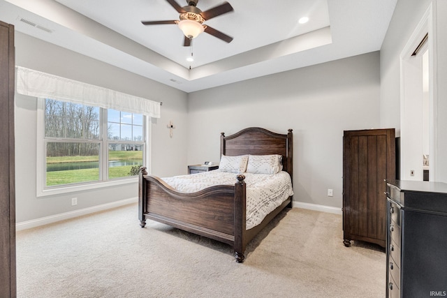 carpeted bedroom featuring a raised ceiling and ceiling fan