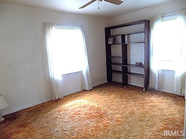 carpeted spare room featuring ceiling fan