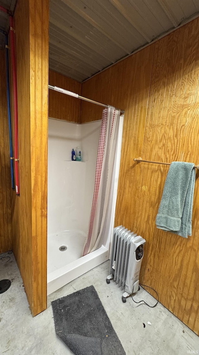 bathroom featuring walk in shower, concrete flooring, radiator, and wood walls