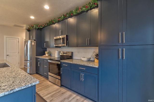 kitchen featuring light stone countertops, stainless steel appliances, tasteful backsplash, light hardwood / wood-style flooring, and blue cabinets