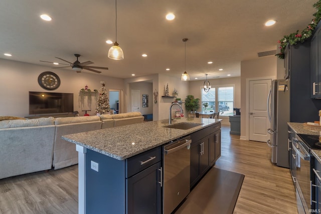 kitchen featuring pendant lighting, a kitchen island with sink, sink, and appliances with stainless steel finishes