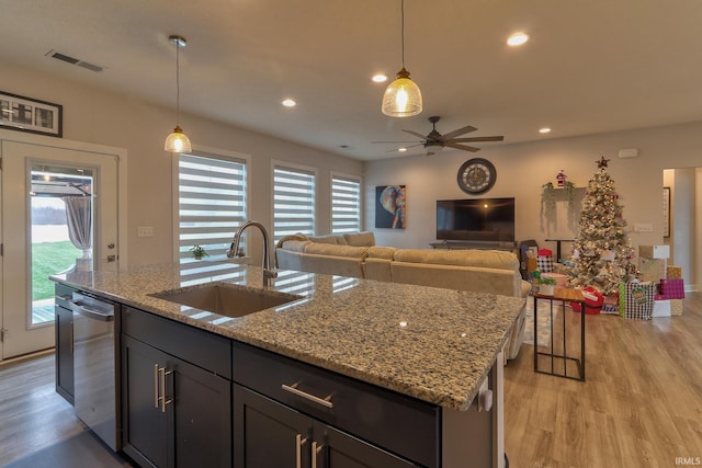 kitchen featuring ceiling fan, sink, light stone counters, stainless steel dishwasher, and decorative light fixtures