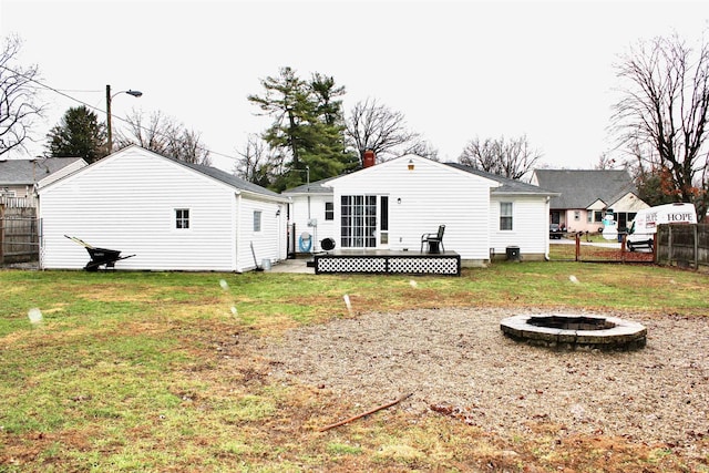 rear view of property featuring a fire pit, a deck, and a lawn