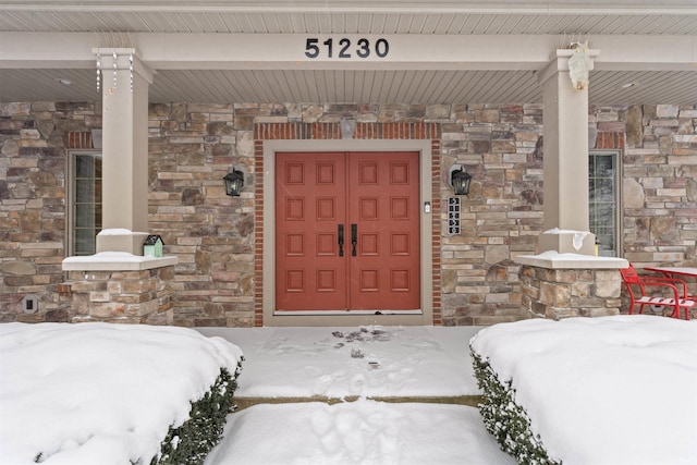 snow covered property entrance featuring covered porch