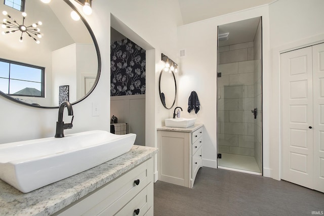 bathroom with a notable chandelier, vanity, lofted ceiling, and tiled shower