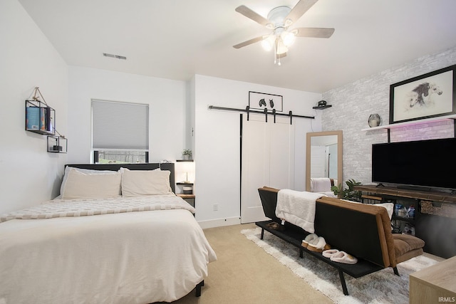 bedroom featuring a barn door, ceiling fan, and light colored carpet