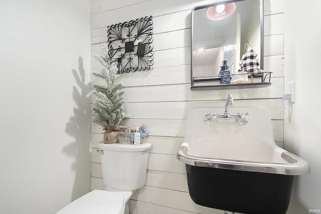 bathroom featuring toilet and wooden walls