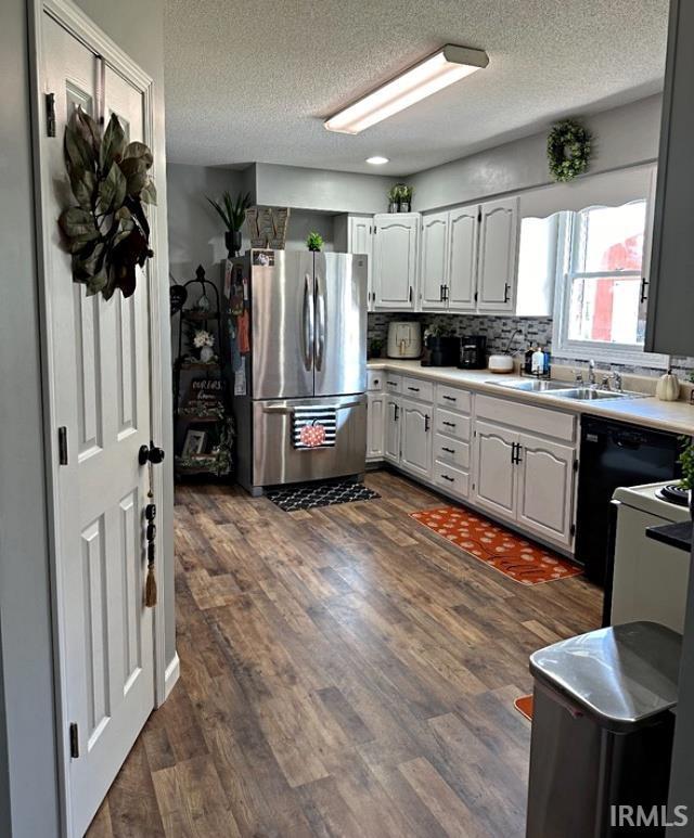 kitchen featuring dark wood-style flooring, freestanding refrigerator, a sink, dishwasher, and tasteful backsplash