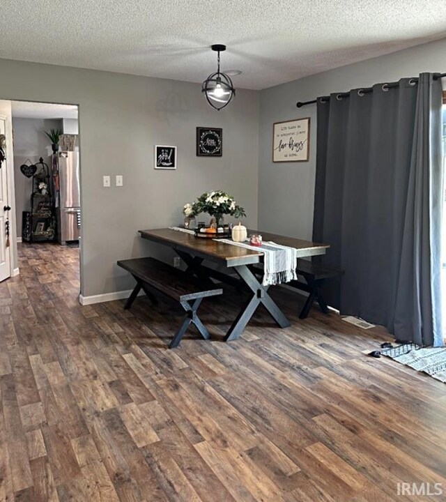 dining area with baseboards, a textured ceiling, and dark wood finished floors