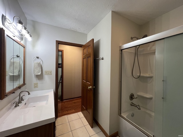 bathroom with tile patterned flooring, vanity, shower / bath combination with glass door, and a textured ceiling