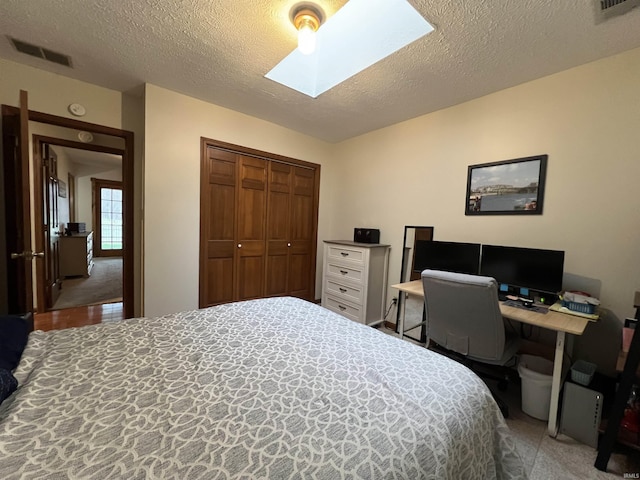 bedroom featuring a textured ceiling, a skylight, a closet, and ceiling fan