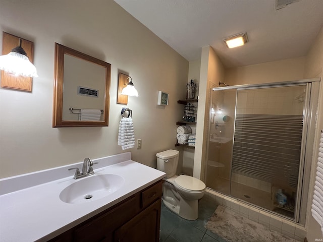 bathroom with tile patterned flooring, vanity, a shower with door, and toilet