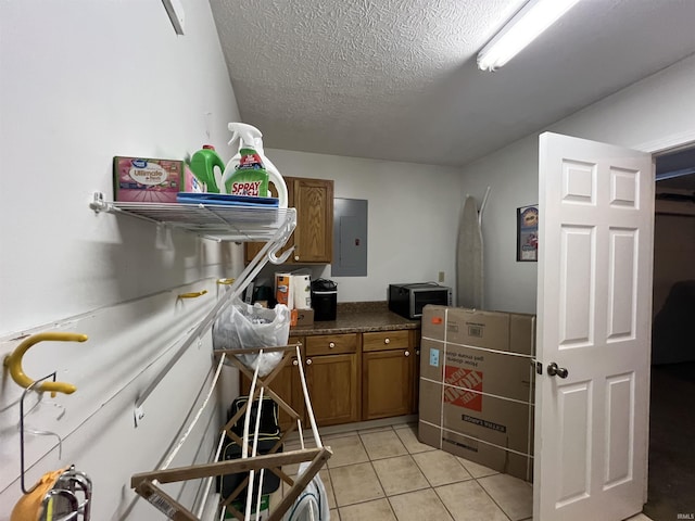 kitchen featuring electric panel, light tile patterned floors, and a textured ceiling