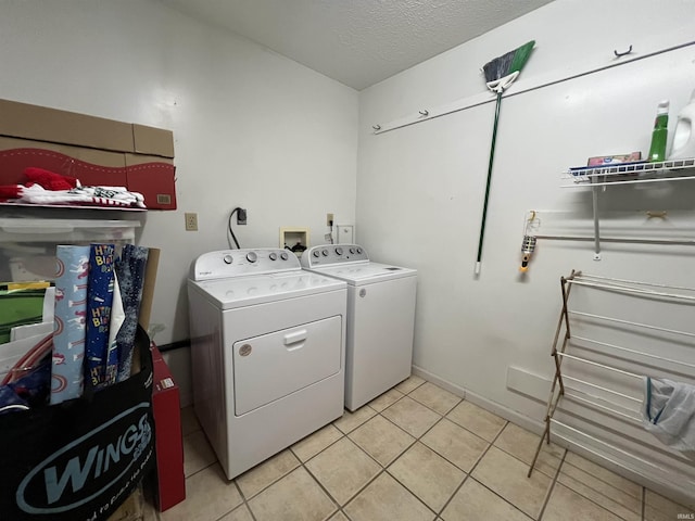 laundry room with light tile patterned floors, a textured ceiling, and washer and clothes dryer