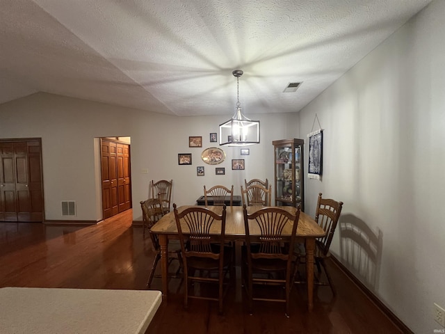 dining room with a textured ceiling, dark hardwood / wood-style flooring, vaulted ceiling, and a notable chandelier