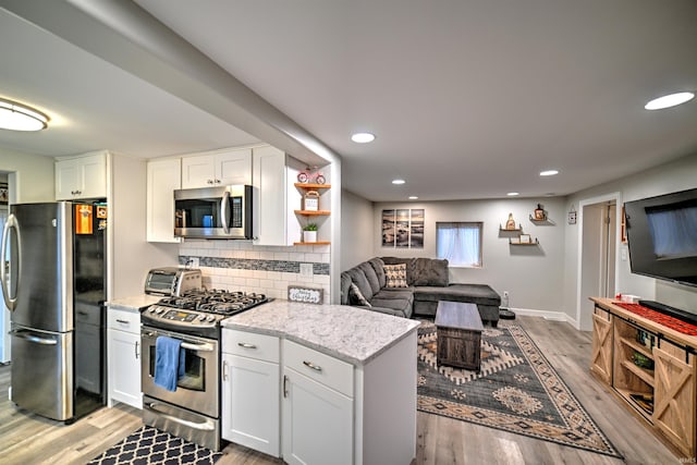 kitchen with white cabinets, decorative backsplash, stainless steel appliances, and light hardwood / wood-style flooring