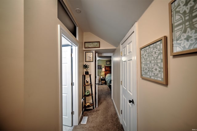 hallway with dark carpet and lofted ceiling