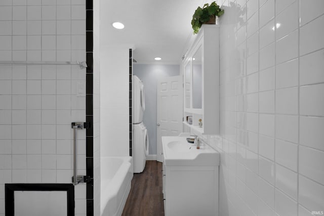 bathroom with vanity, ornamental molding, a tub to relax in, tile walls, and wood-type flooring