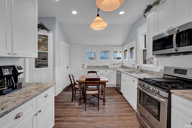 kitchen with light stone counters, sink, hanging light fixtures, and appliances with stainless steel finishes