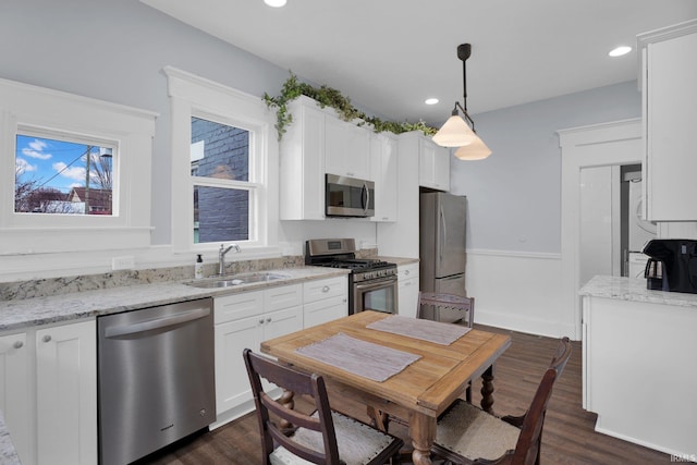 kitchen featuring pendant lighting, sink, white cabinets, and stainless steel appliances