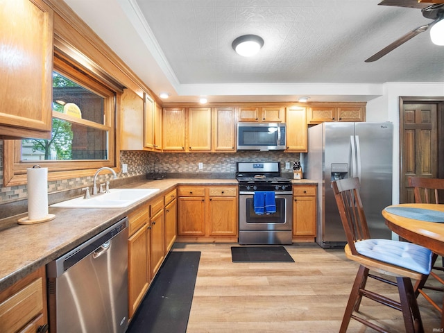 kitchen featuring crown molding, sink, decorative backsplash, light wood-type flooring, and appliances with stainless steel finishes