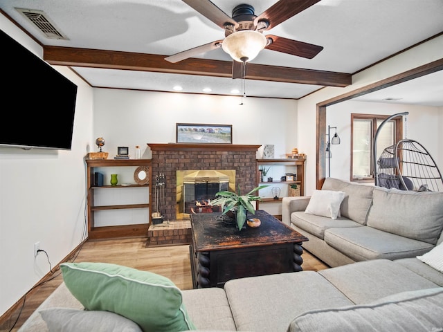 living room with beamed ceiling, light wood-type flooring, a brick fireplace, and ceiling fan