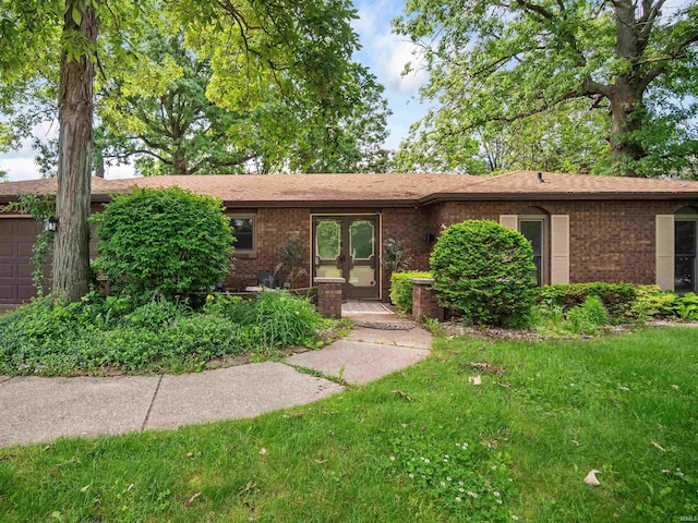 ranch-style home with french doors, a front yard, and a garage