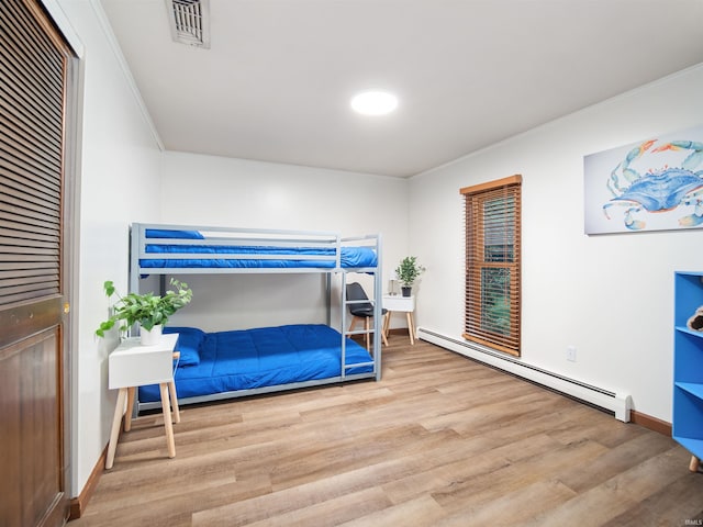 bedroom featuring hardwood / wood-style floors and a baseboard heating unit