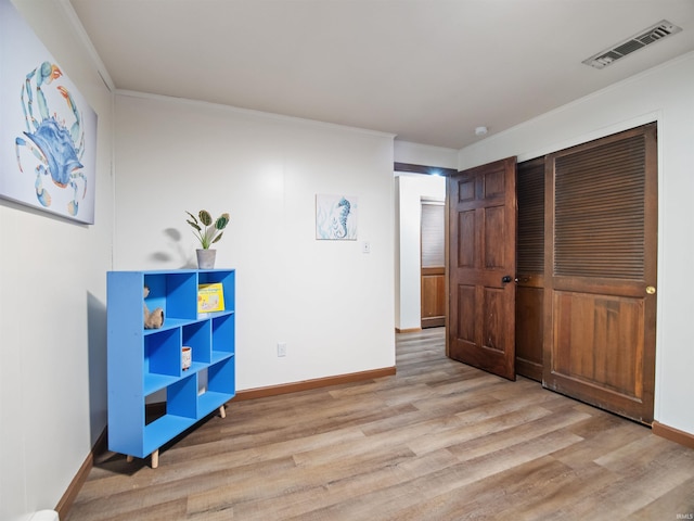 bedroom with light hardwood / wood-style floors and ornamental molding