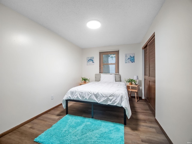 bedroom featuring dark hardwood / wood-style flooring and a textured ceiling