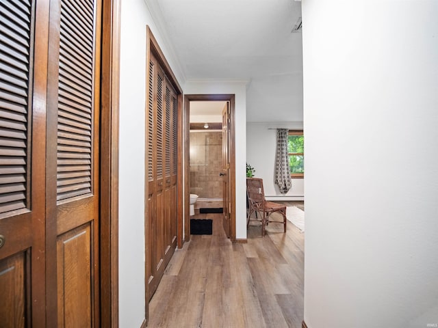 hall featuring a baseboard heating unit, light wood-type flooring, and ornamental molding