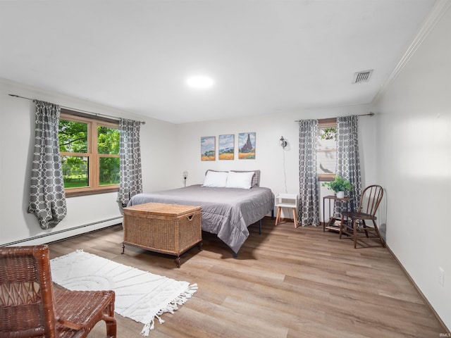 bedroom featuring baseboard heating, crown molding, and light hardwood / wood-style floors