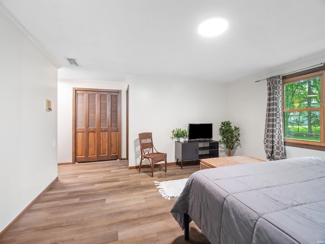 bedroom featuring light wood-type flooring, a closet, and crown molding