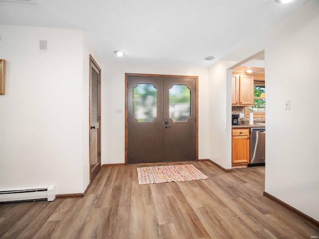 foyer entrance with light wood-type flooring, french doors, and a baseboard radiator