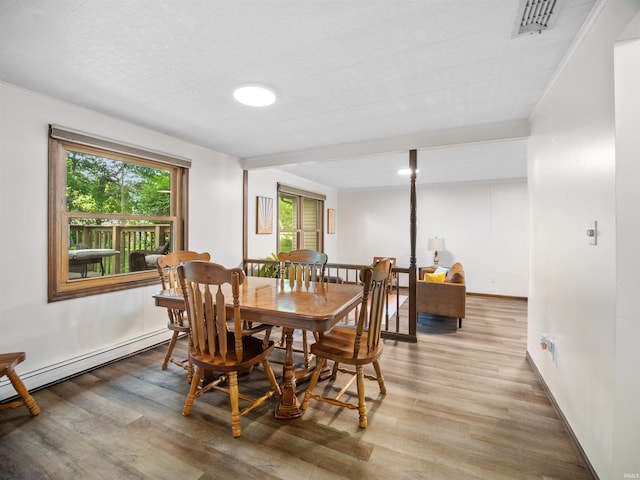 dining space with a baseboard heating unit and hardwood / wood-style flooring