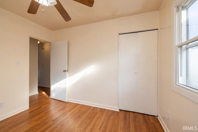 unfurnished bedroom with ceiling fan, wood-type flooring, multiple windows, and a closet