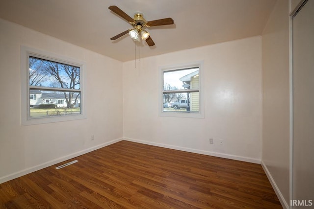 spare room featuring ceiling fan, plenty of natural light, and dark hardwood / wood-style floors