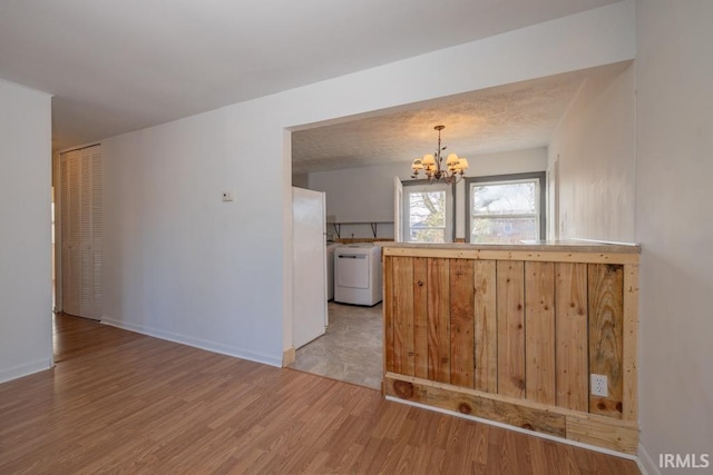 kitchen with light hardwood / wood-style flooring, an inviting chandelier, white refrigerator, and washer / dryer