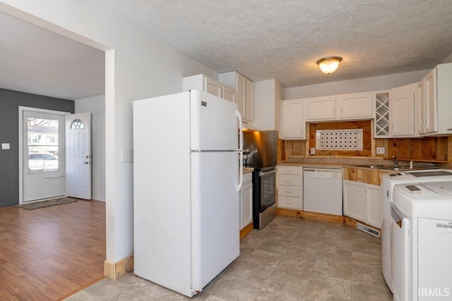 kitchen with white cabinets, washer / dryer, white appliances, and sink