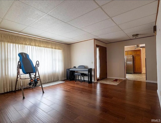 workout area featuring a paneled ceiling, ceiling fan, and hardwood / wood-style floors