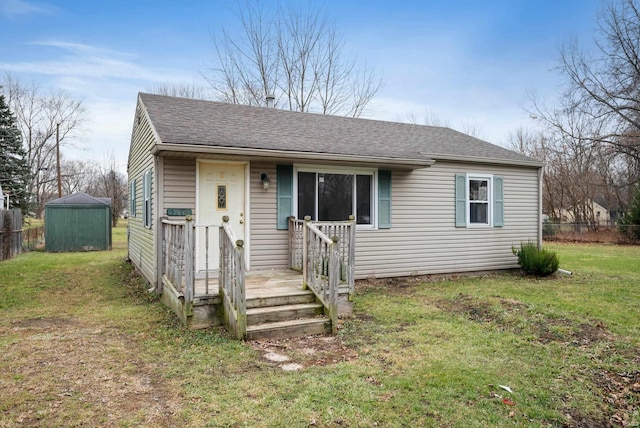 view of front of house with a front yard and a shed