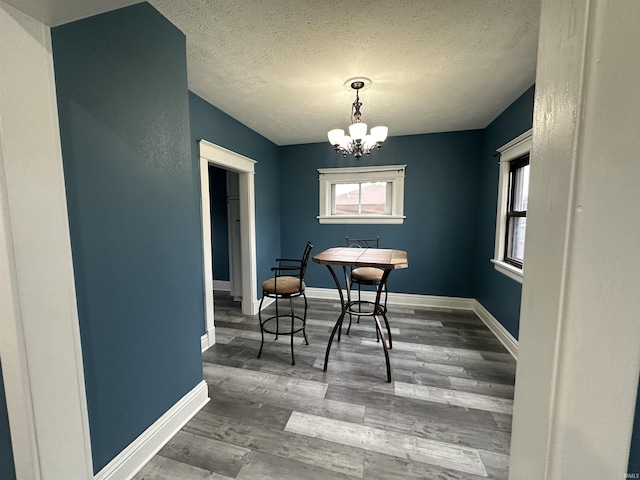 dining space with a notable chandelier, a textured ceiling, and dark wood-type flooring