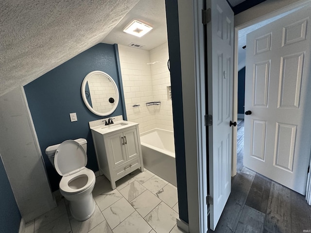 full bathroom with vanity, lofted ceiling, tiled shower / bath combo, toilet, and a textured ceiling