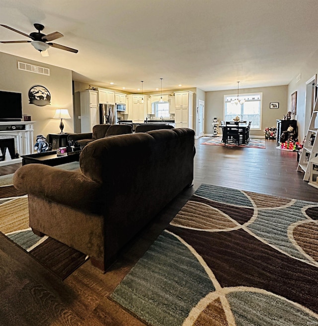 living room with ceiling fan with notable chandelier and dark hardwood / wood-style floors