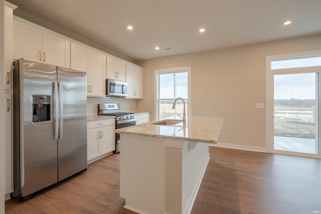 kitchen with white cabinets, sink, stainless steel appliances, and an island with sink