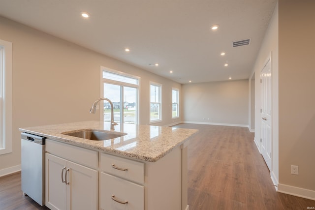 kitchen featuring light stone countertops, a kitchen island with sink, sink, dishwasher, and white cabinetry