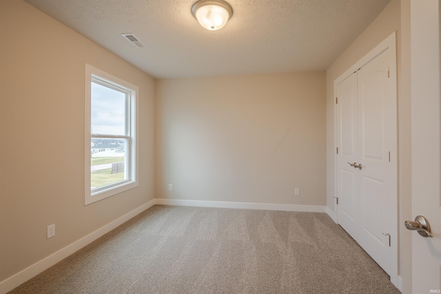 carpeted empty room featuring a textured ceiling